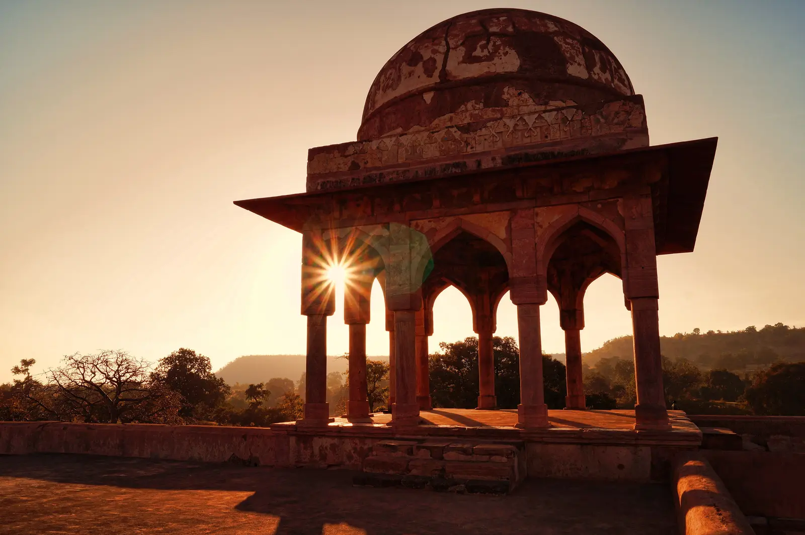 Domed stone baradari on the terrace of Baz Bahadur's Palace, Mandu, with the setting sun shining through its arches