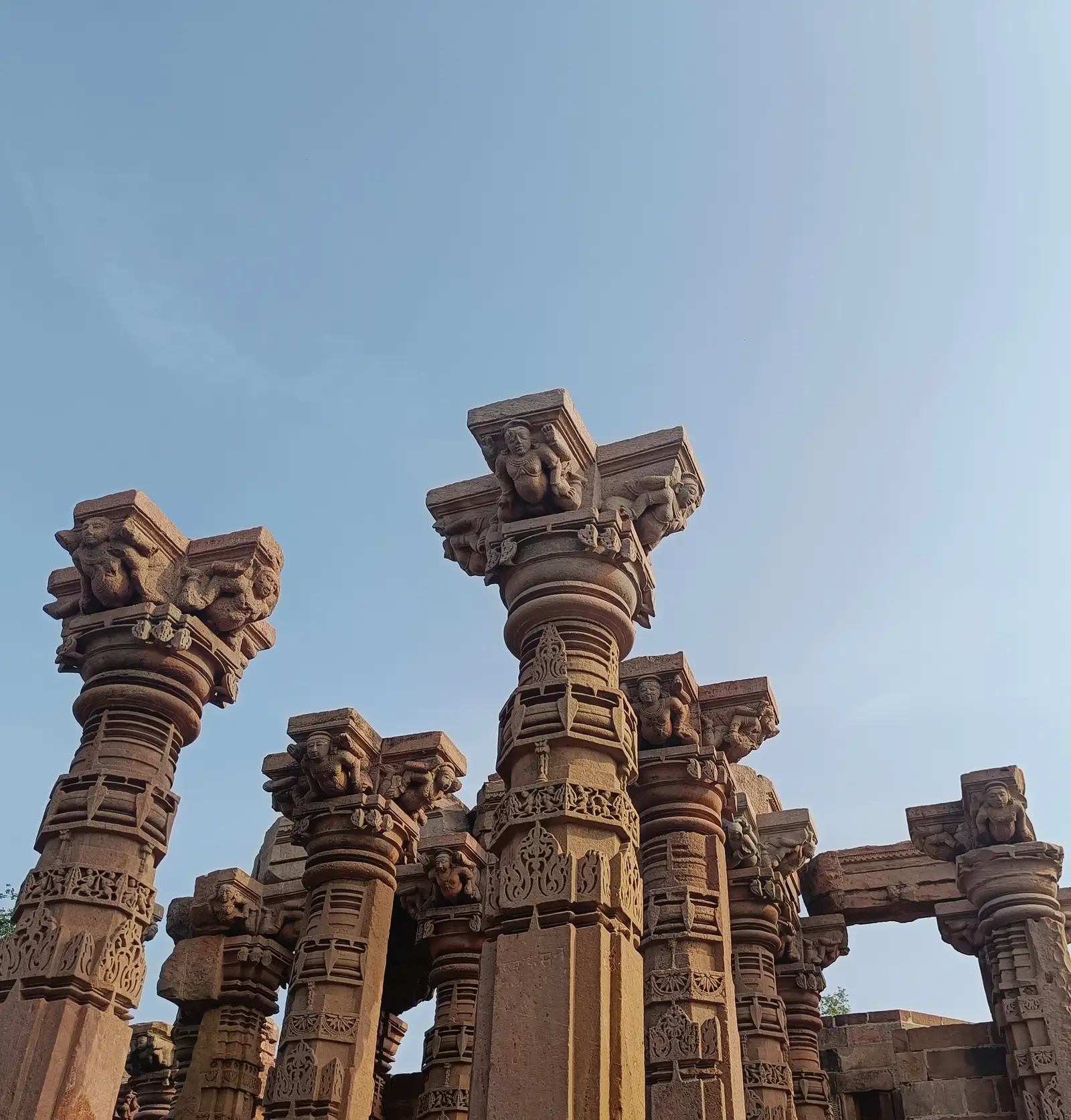 Carved stone pillars of the Siddhnath temple on Mandhata island, Omkareshwar, standing against a pale sky