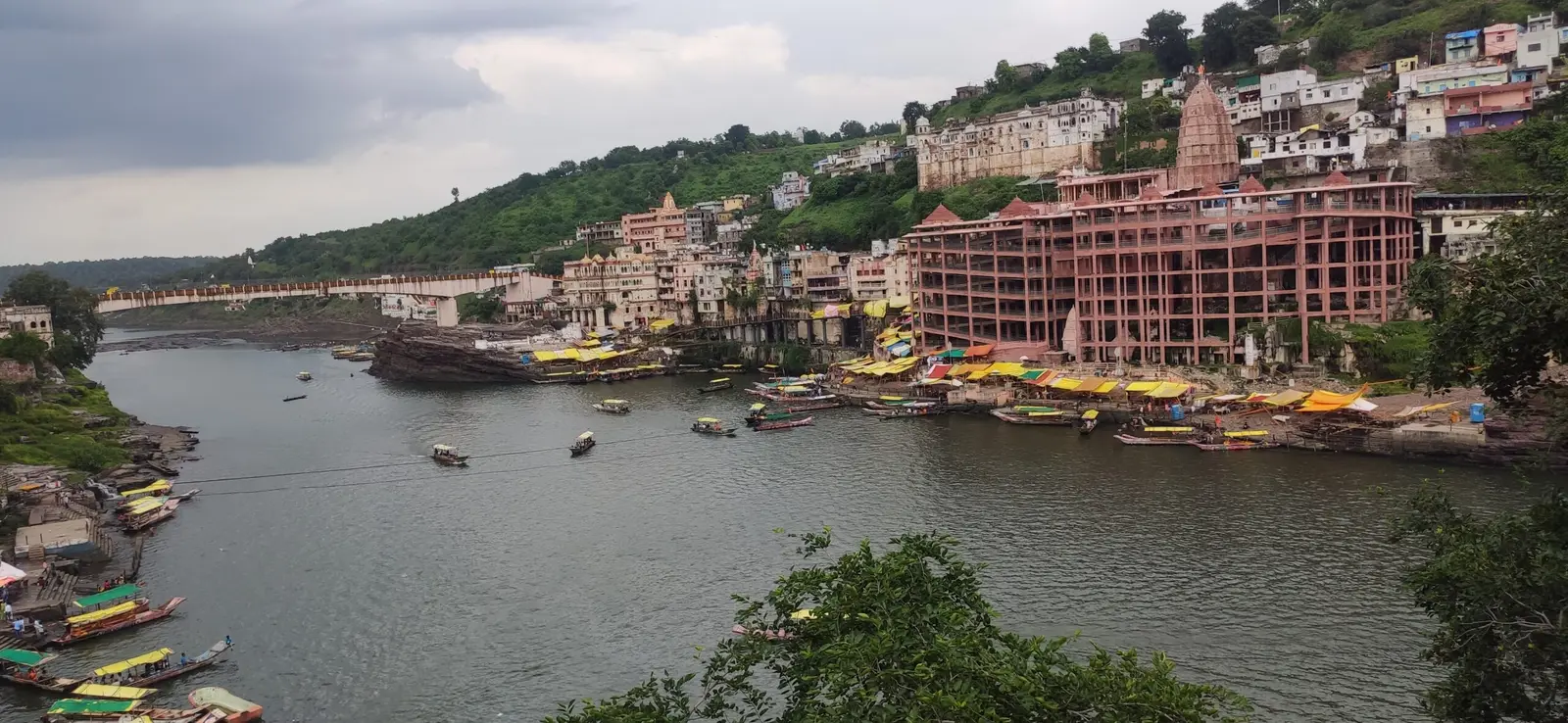 Omkareshwar temple complex and ghats on Mandhata island, seen from across the Narmada with boats on the river