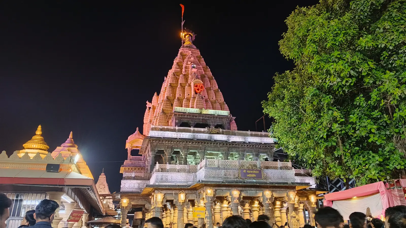 रात में रोशनी से जगमगाता उज्जैन का महाकालेश्वर मंदिर, अंधेरे आसमान के सामने उसका सीढ़ीनुमा शिखर