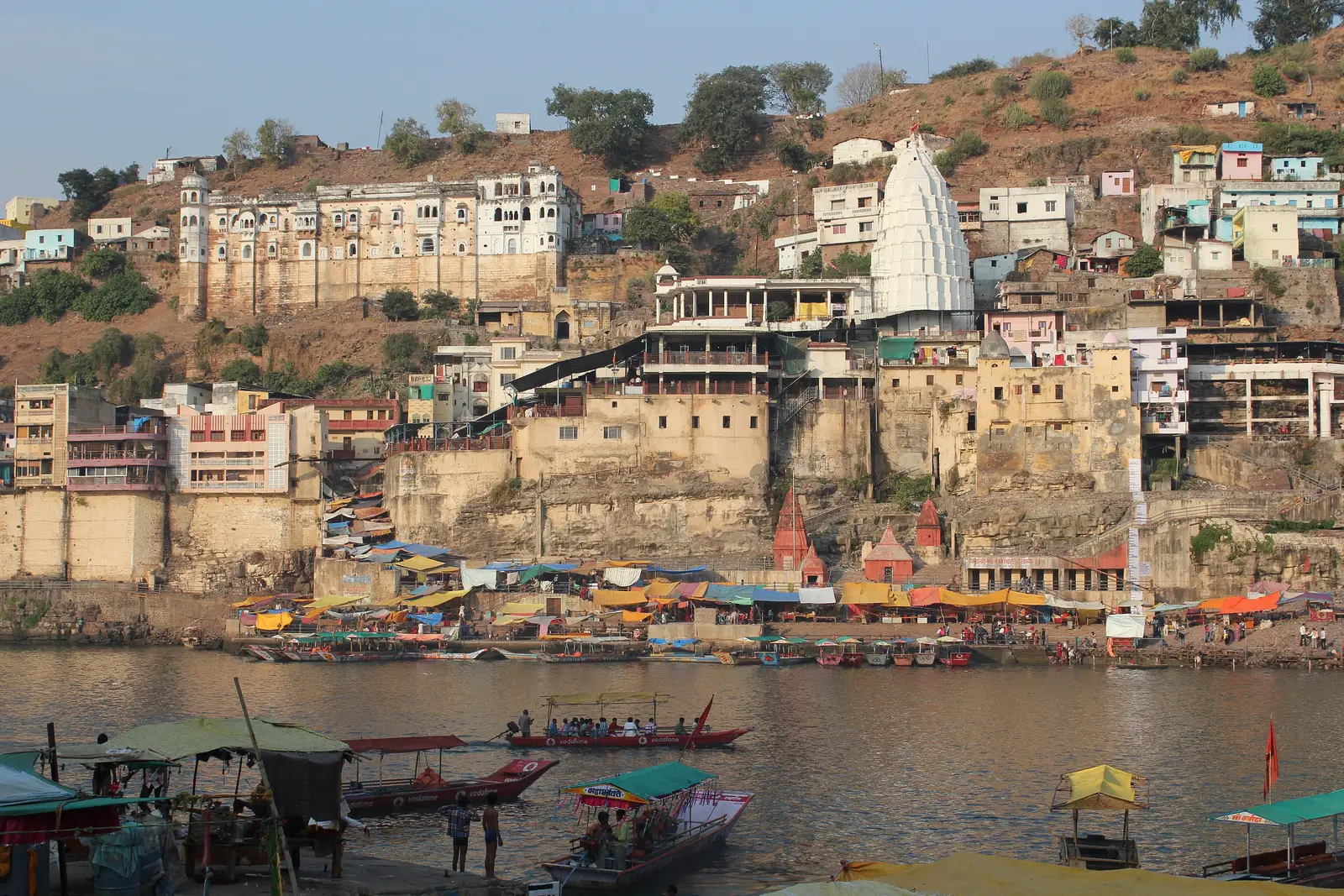 Omkareshwar temple and town rising from the ghats of Mandhata island, with boats moored on the Narmada