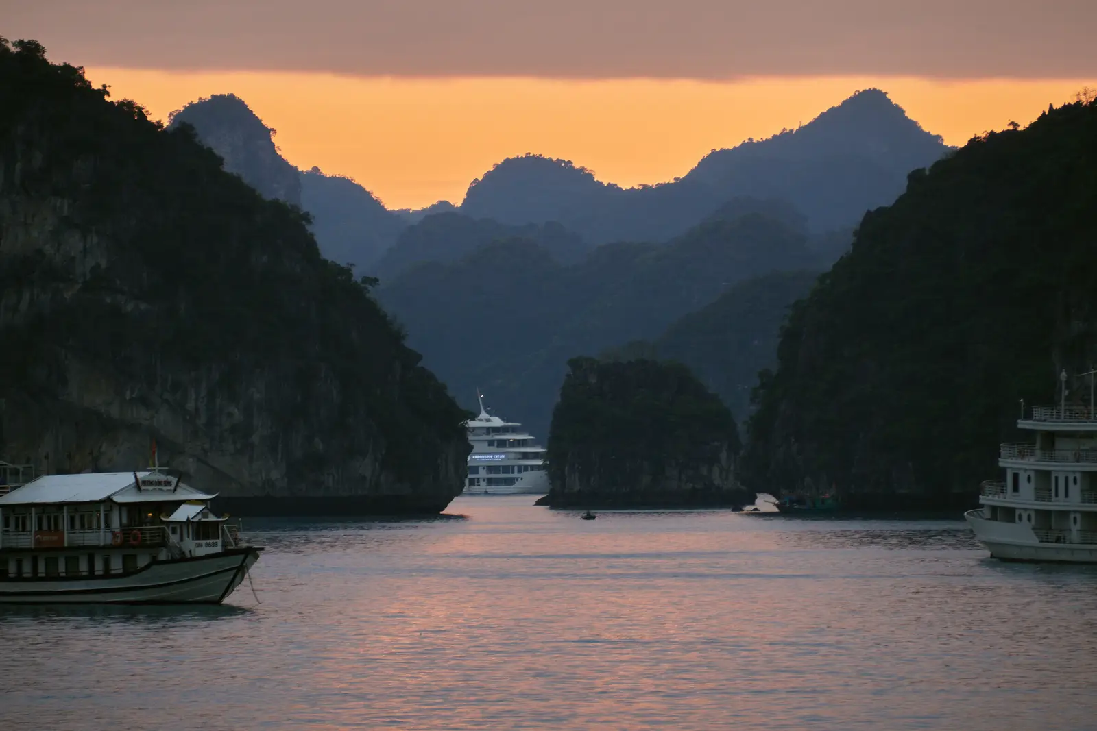Cruise boats among limestone karsts in Ha Long Bay, Vietnam, at dusk